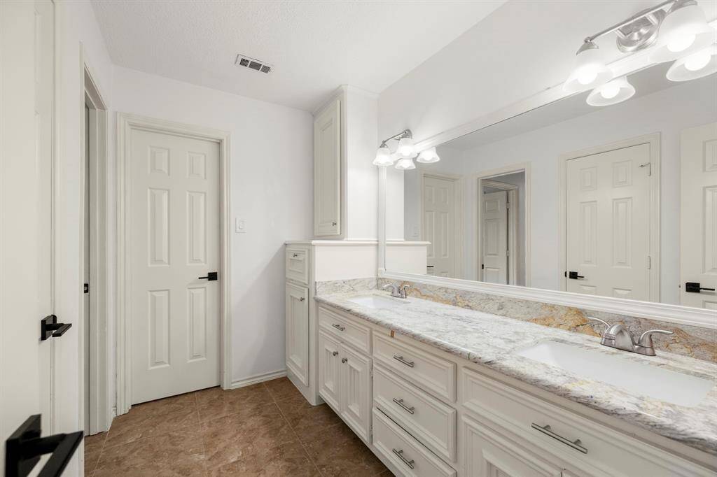 Inside the bathroom, you'll find granite counters and dual sinks, offering plenty of space for daily routines. The cabinets provide ample storage, keeping the space organized and functional while maintaining a sleek, modern look.