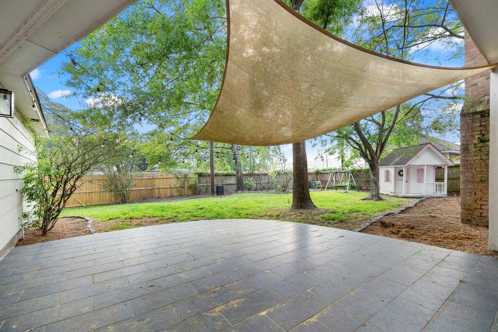 The back patio offers a perfect spot for outdoor relaxation, with a view of the spacious yard beyond. The playhouse adds a charming touch to the backyard, providing a fun and imaginative space for outdoor activities.