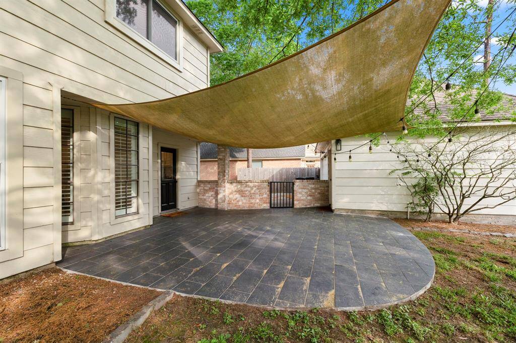 From the yard, this view of the back patio shows the home’s inviting exterior, with the detached garage visible on the right. The spacious yard offers plenty of room for outdoor activities, making this area perfect for both relaxation and entertaining.