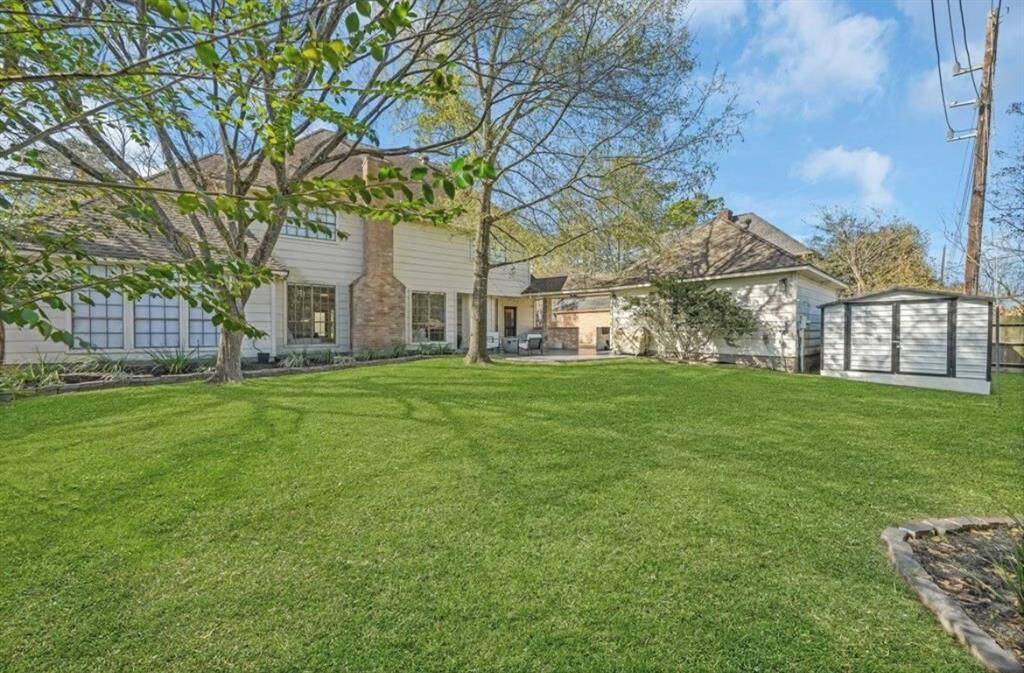 A better view of the yard looking back at the home reveals the spacious area, perfect for outdoor activities. The storage shed is tucked behind the detached garage, offering additional space for organization and tools while maintaining the neat, open feel of the yard.