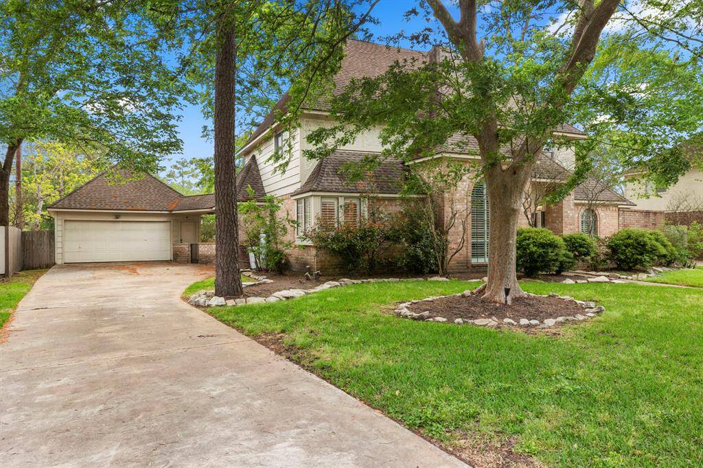 Another view of the front of the home highlights the detached garage and ample driveway space, offering plenty of room for parking and easy access. The landscaping adds to the home's curb appeal, creating an inviting entrance.