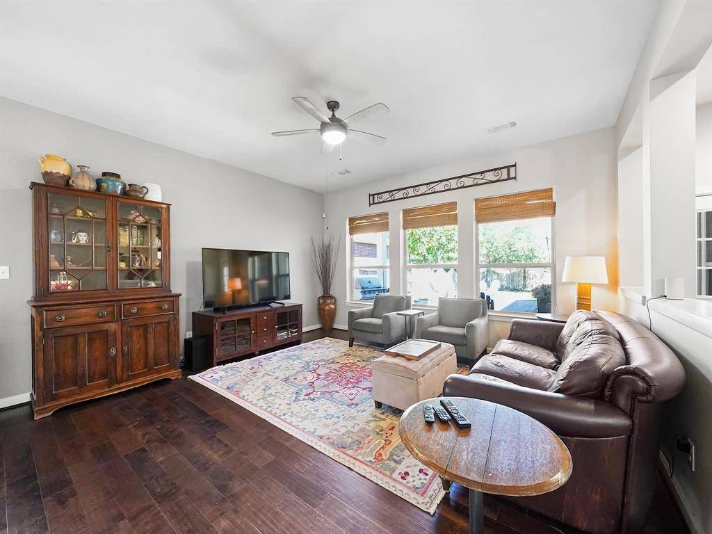 The beautiful living room is bathed in natural light, thanks to a wall of windows that overlook the serene backyard.
