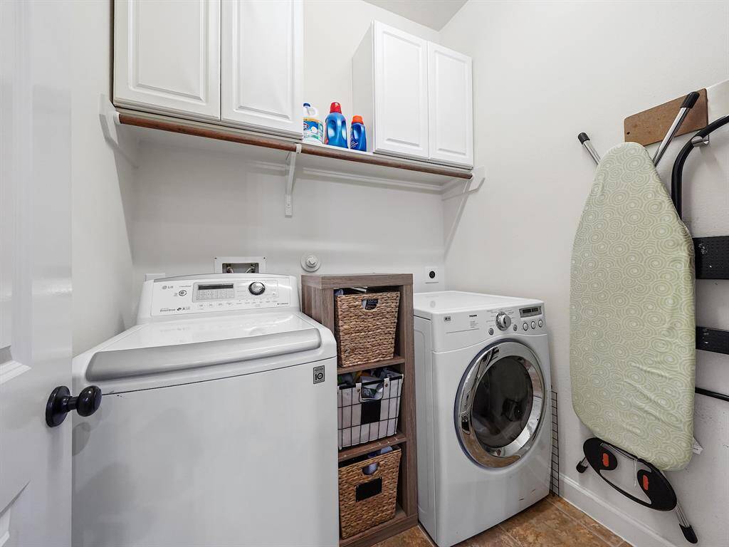 he conveniently located utility room offers built-in cabinets, providing additional storage for laundry supplies and other household items.