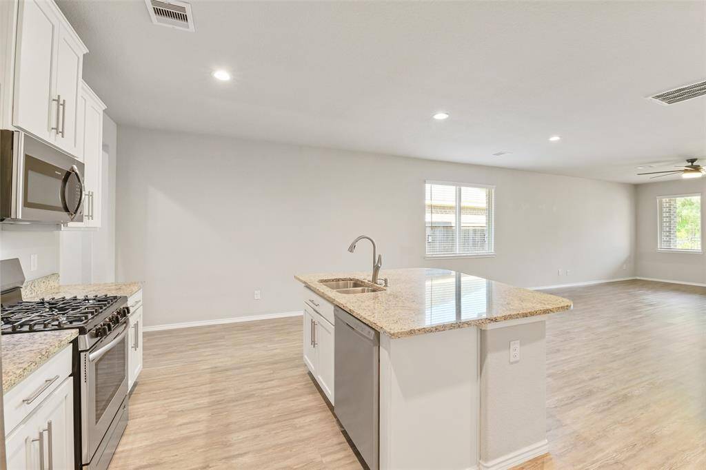 Wide open kitchen layout with large island, gas range, and plenty of cabinets for storage.