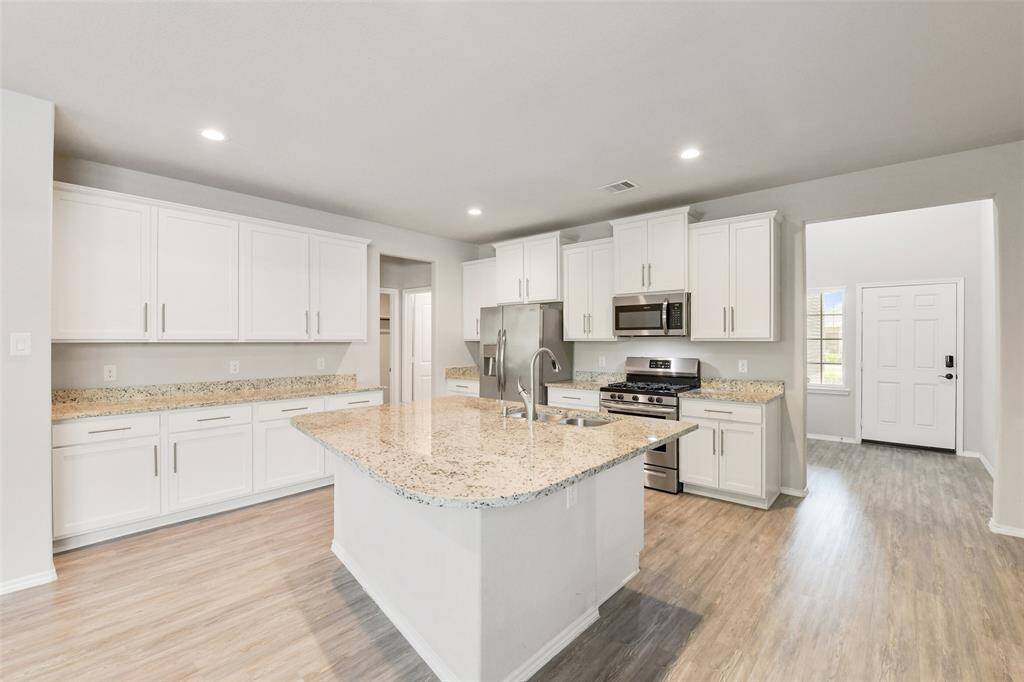 Wide open kitchen layout with large island, gas range, and plenty of cabinets for storage.