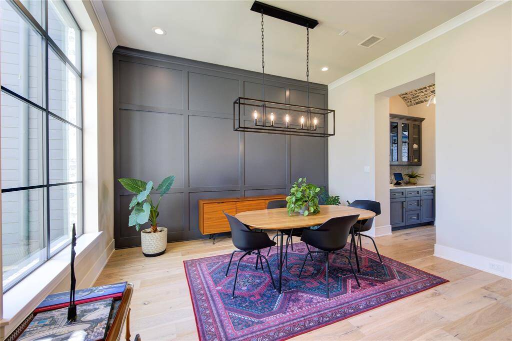 Elegant dining room featuring a modern chandelier, chic paneling, and abundant natural light, perfect for gatherings and memorable meals.