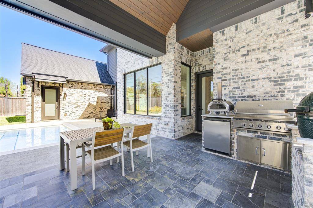 Luxurious outdoor kitchen with modern grill, pizza oven, and spacious dining area—perfect for entertaining.