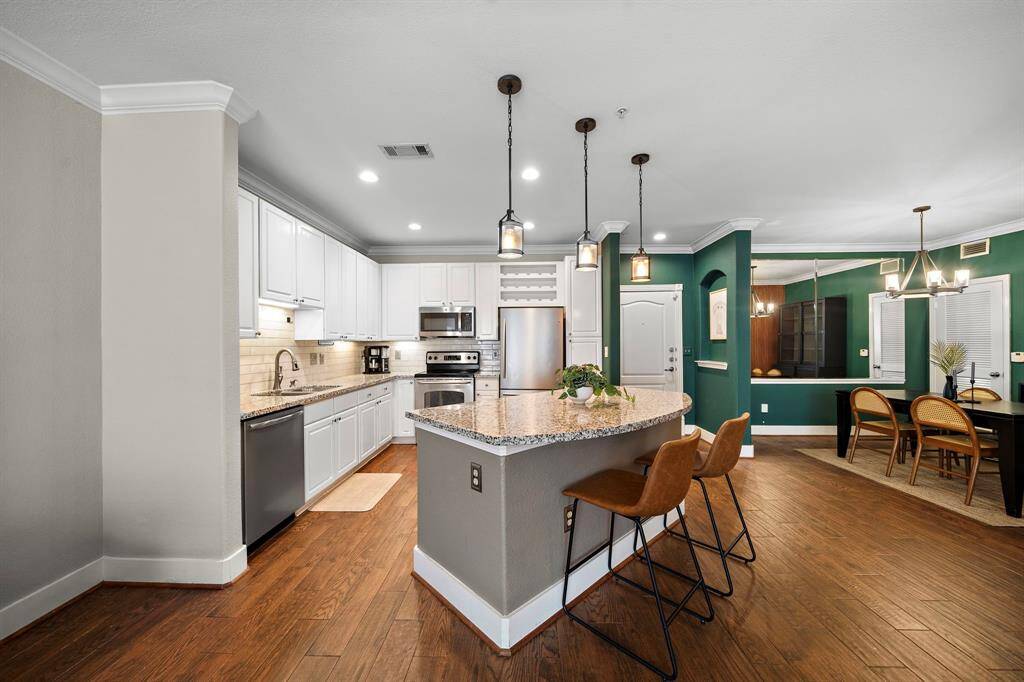The remodeled kitchen is a contemporary masterpiece with expansive cabinetry, granite countertops, and a modern backsplash. An oversized island and stainless steel appliances provide both style and functionality, seamlessly connecting to a casual dining space for easy entertaining.