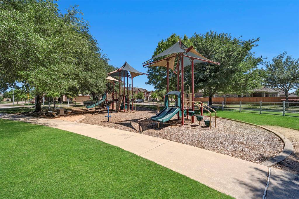 This photo showcases a room-to-roam backyard with a patio and a wooden pergola adjacent to a brick house. The area features a well-maintained lawn, which is fenced for privacy, and offers ample space for outdoor relaxation or entertaining.