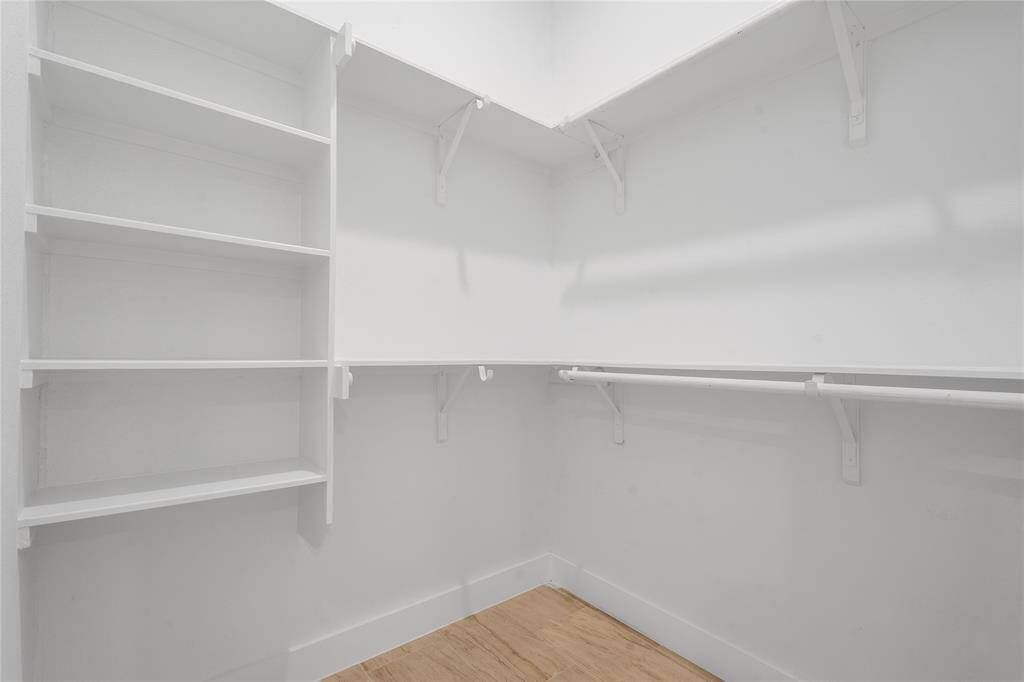 Primary walk-in closet with ample shelving and hanging rods