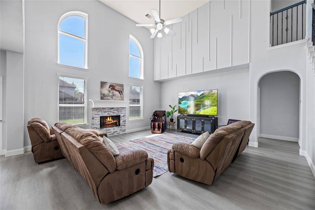 Impressive living room featuring soaring ceilings, a cozy modern fireplace, and elegant architectural wall detailing—perfect for relaxing or entertaining.
