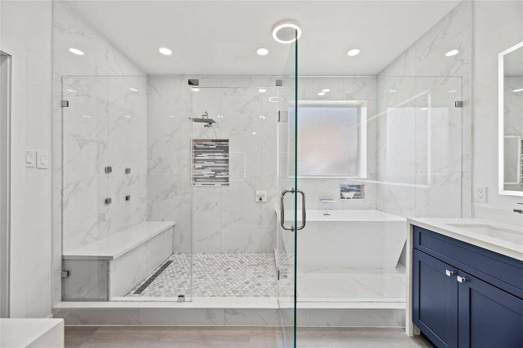 Super shower with rain shower head and soaking tub with elegant tile throughout.