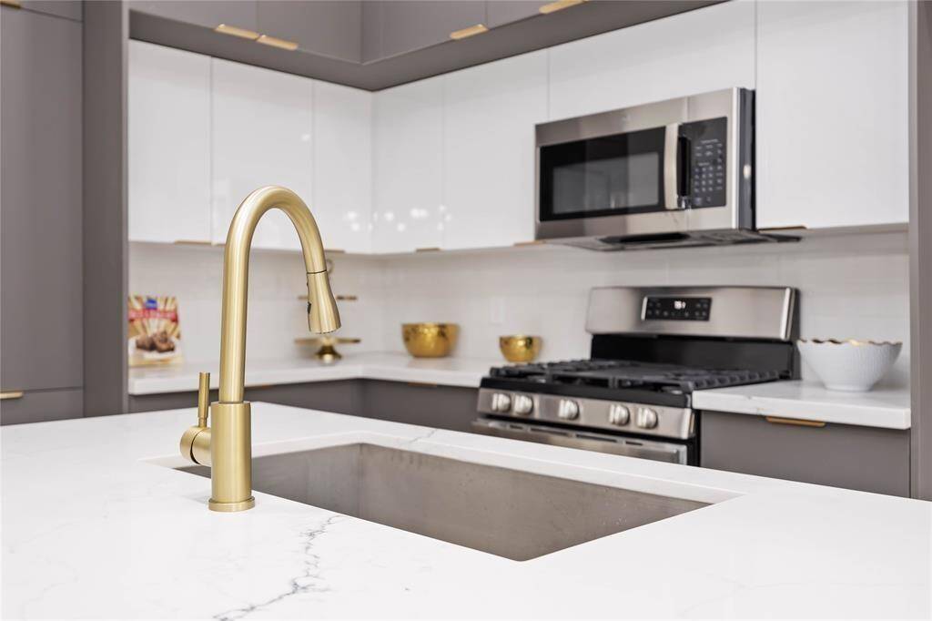Clean lines, a large island, and brushed gold fixtures provide a sleek and modern space. Abundant cabinets over and under the counters and pantry provide for plenty of storage for all your cooking and prepping needs.