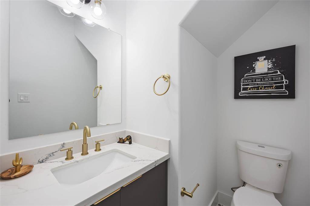 The powder room on the first floor is spacious. Brushed gold fixtures throughout highlight the modern aesthetic the home.