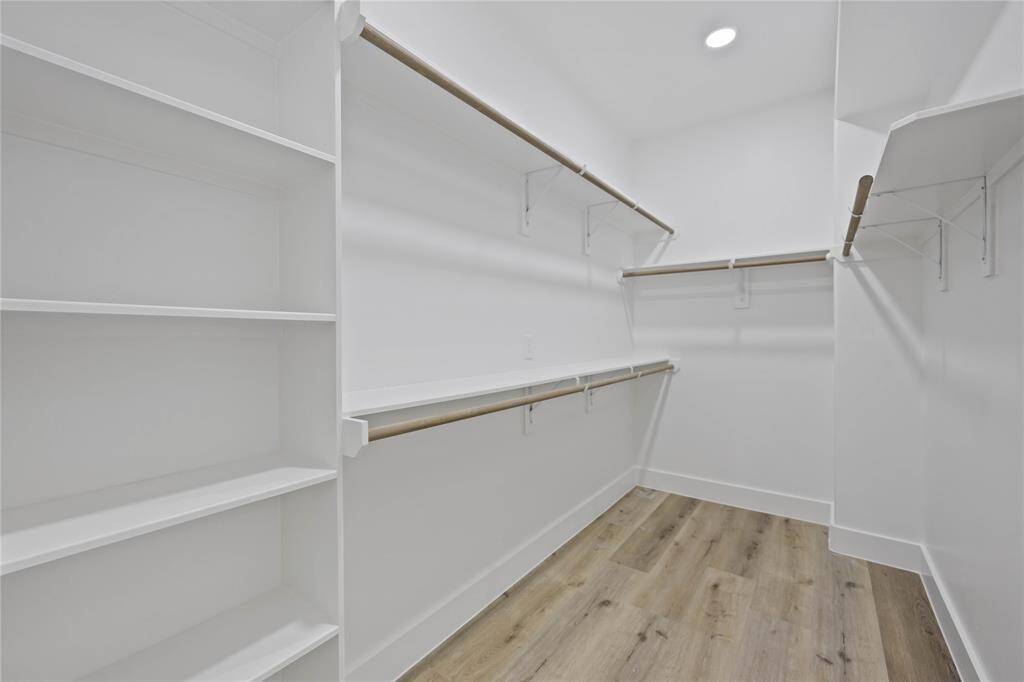 The oversized closet in the primary suite provides ample storage with built-in shelves and rods for hanging coats, dresses, shoes and bags.