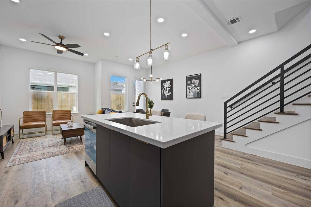 The island is open to the living and dining areas and features sleek light fixtures and quartz countertops. Gorgeous floors adorn this sleek living space.