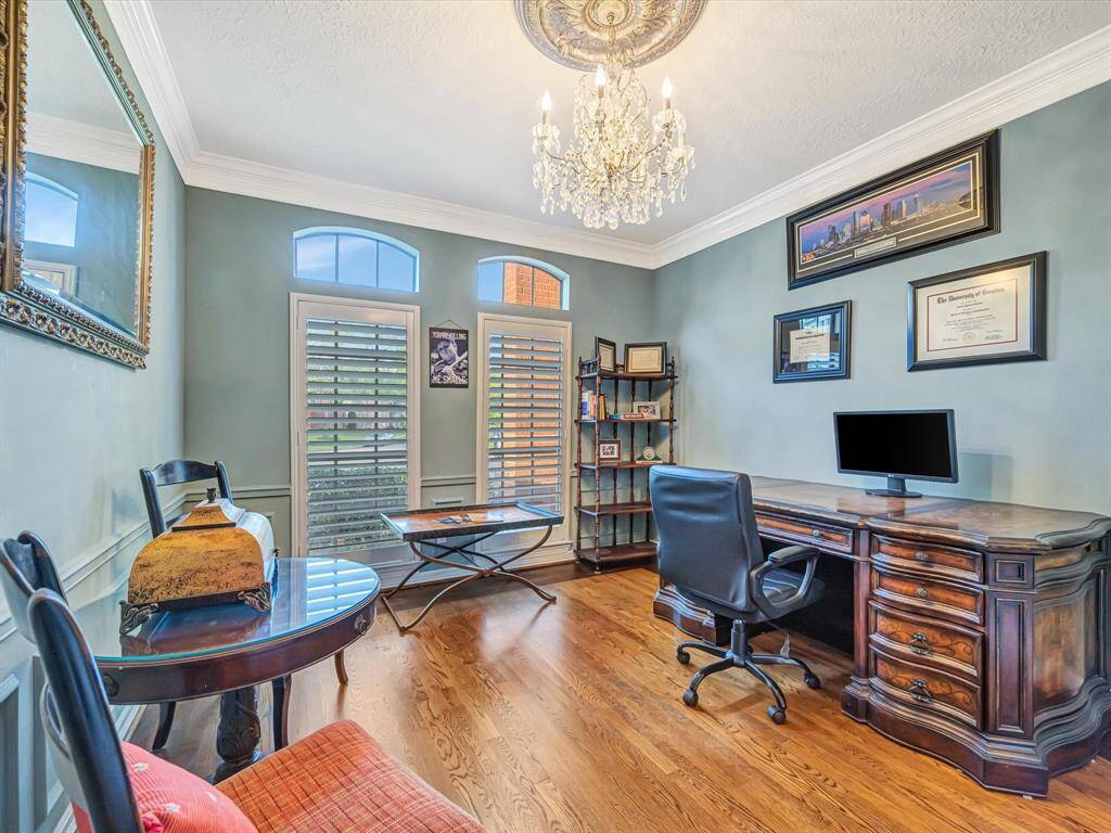 This photo shows an elegant home office with hardwood floors, a large wooden desk, and a comfortable office chair -  a multi-functional space.