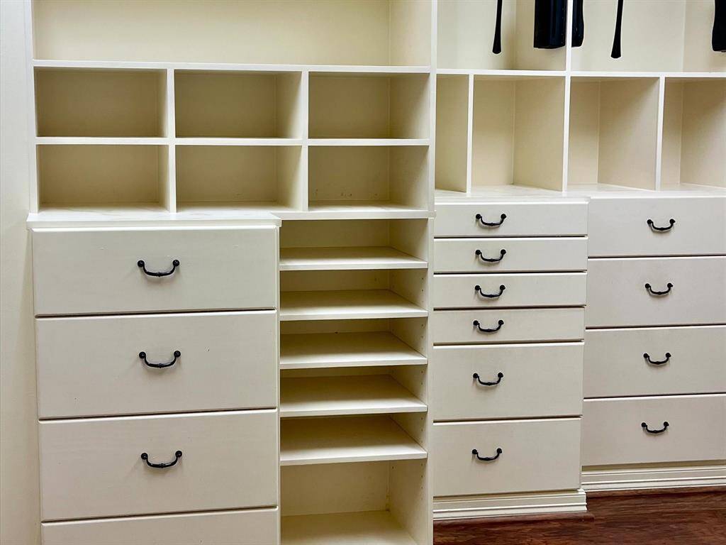This photo shows a spacious built-in closet system with multiple shelves and drawers, ideal for organized storage. The units have a clean, white finish and black handles, offering ample space and functionality.
