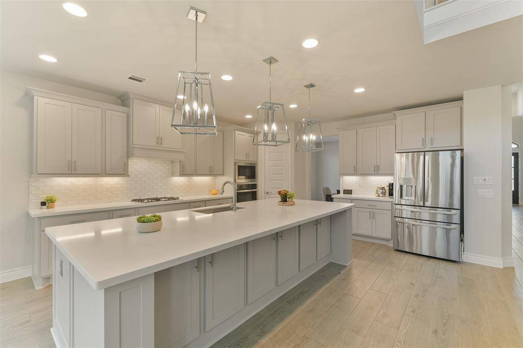Quartz counters on the oversized island top cabinets on both sides, giving ample storage space for all the kitchen essentials. Pendant lights over the breakfast bar and undercabinet lighting make sure the entire kitchen is light and bright.