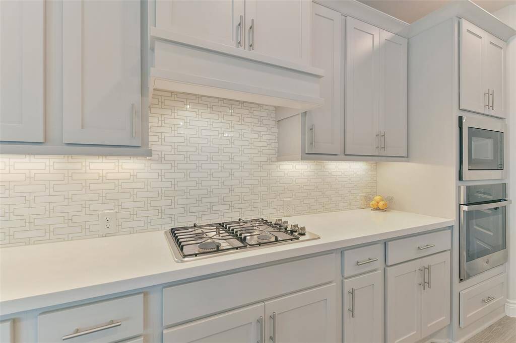 Designer backsplash and upgraded vent hood over the gas cooktop add elegance to this already gorgeous kitchen.