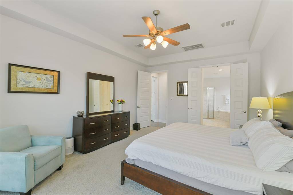 Primary bedroom with its trayed ceiling opens to a luxury bath.