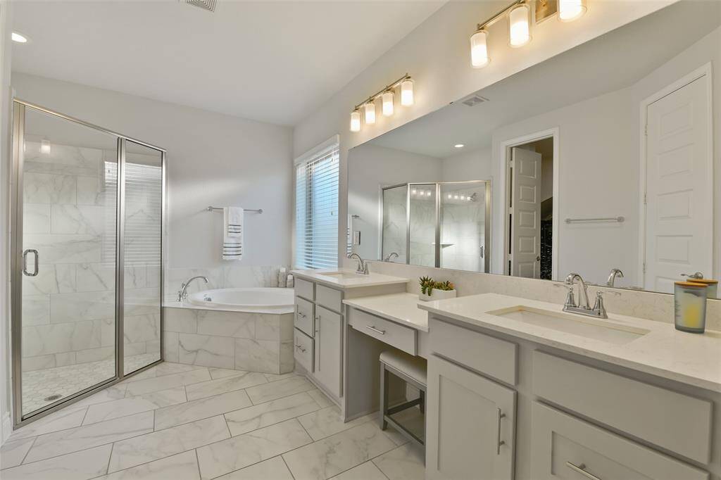 This spa like primary bath has double sinks, a vanity area, wall long mirror, soaking tub, and separate large shower.