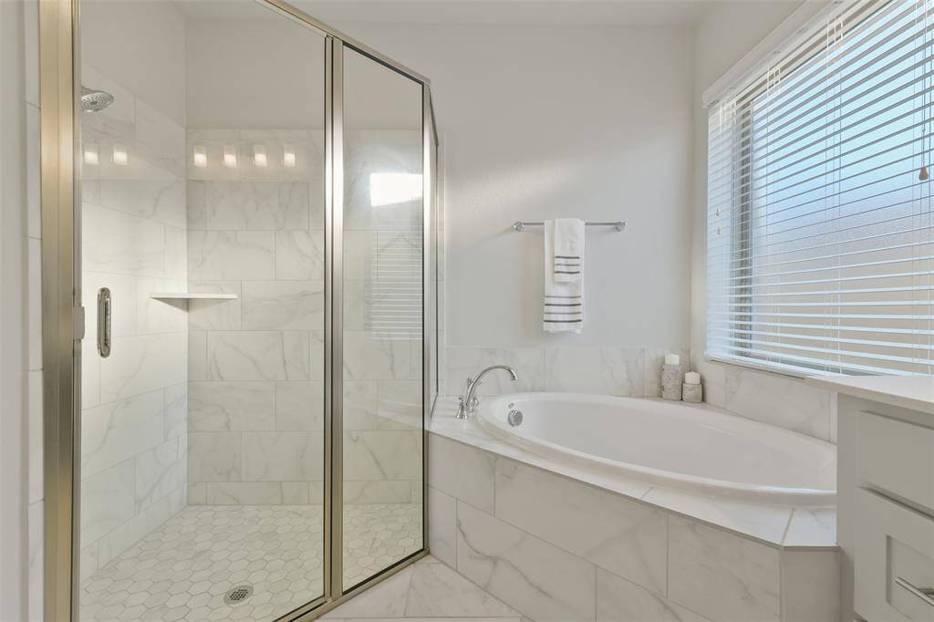 The frosted window allows natural light to flood this primary bath with its soaking tub and mudset shower.