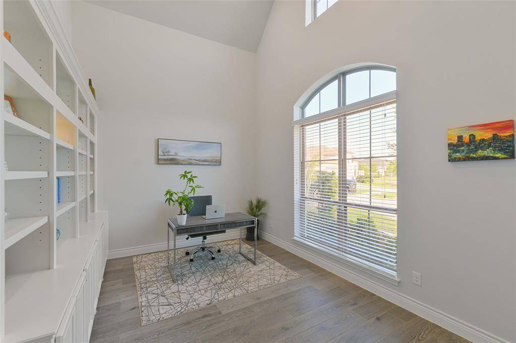 Study has 17 foot high ceiling, arched lower window, plus higher window, ceramic wood look tile, and built-in bookcases.