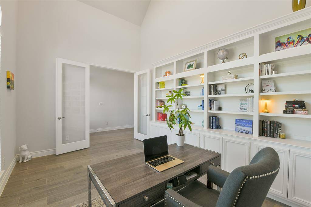 French doors lead off the front entry to this airy study with 17 foot ceiling and custom built-in bookcases.