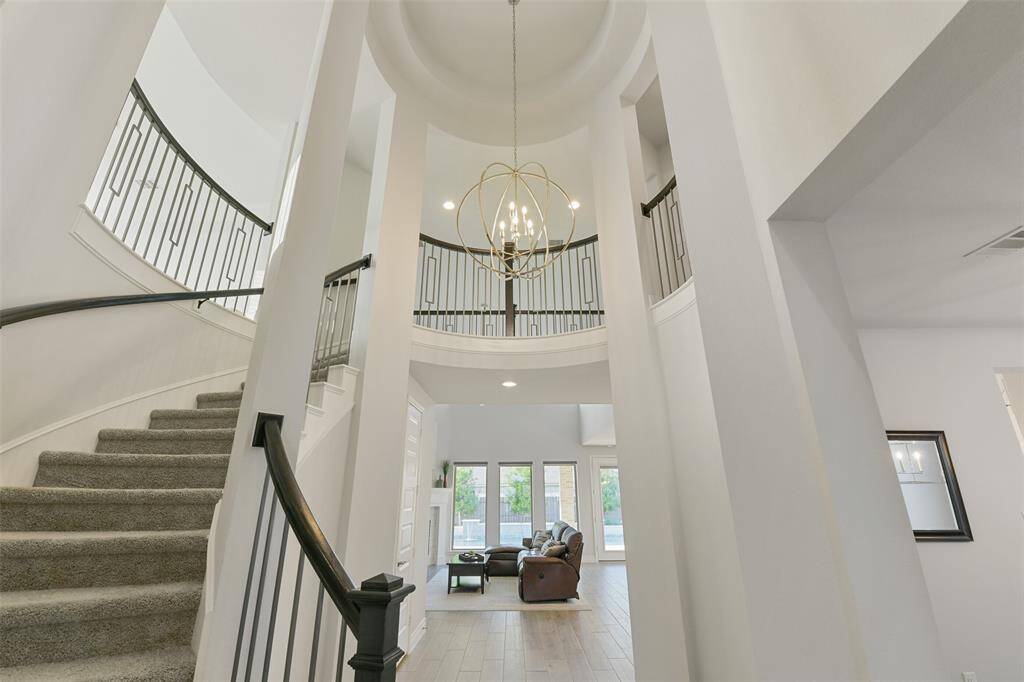 Curving staircase leading to upstairs balcony and game room is highlighted by a rotunda with trayed ceiling and elegant chandelier.