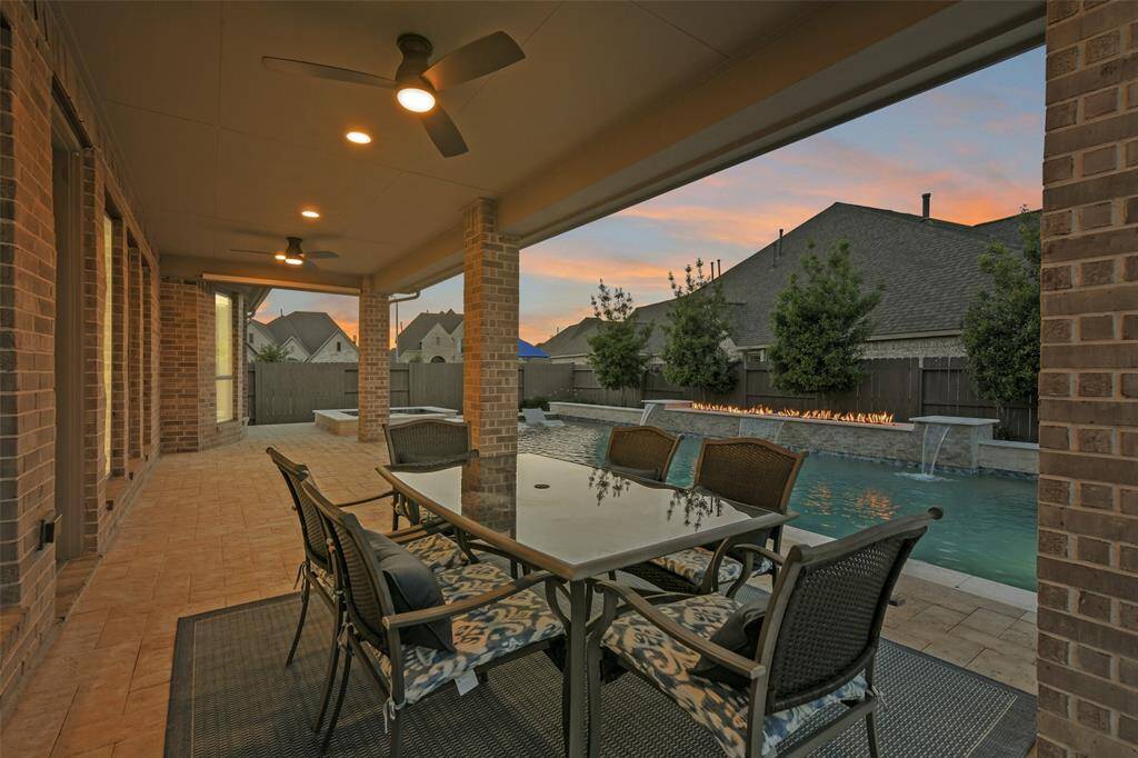 This extended covered back porch has plenty of space to extend your living outdoors and connects seamlessly to the spa and pool with 4 waterfalls and a fire feature. The space behind the pool is professionally landscaped, including large trees.