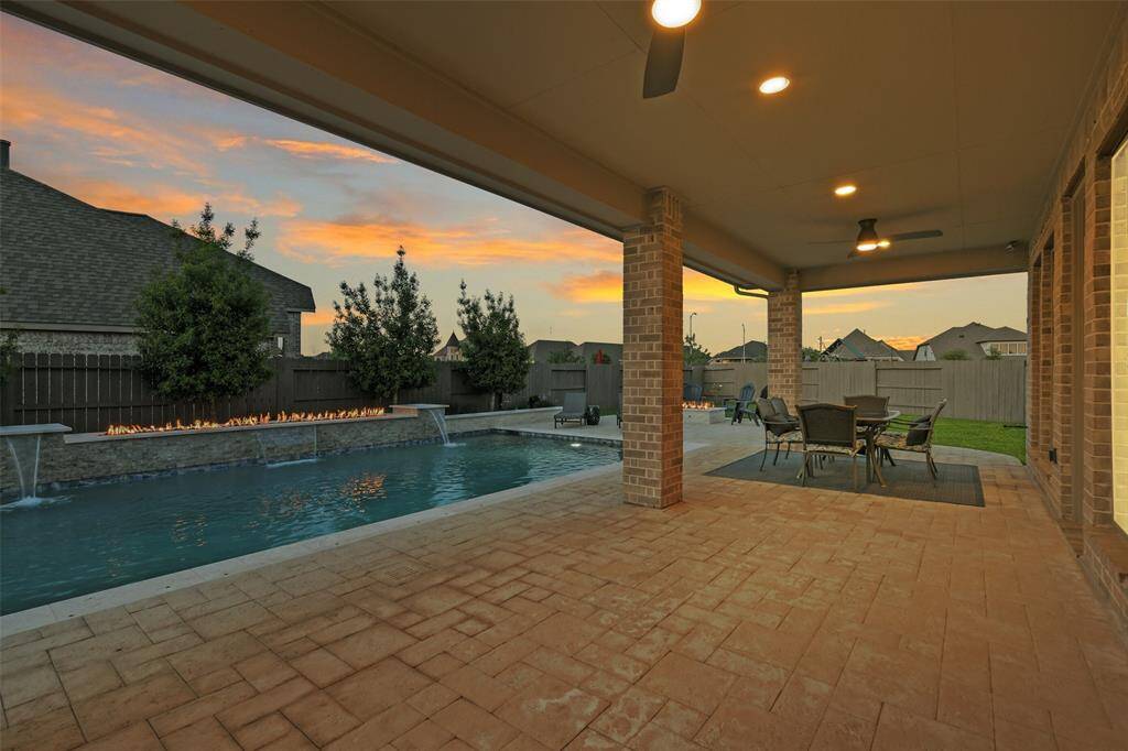 Large extended covered porch includes ceiling fans and a gas stub, plus ample access to the beautiful pool with its waterfalls and fire feature.