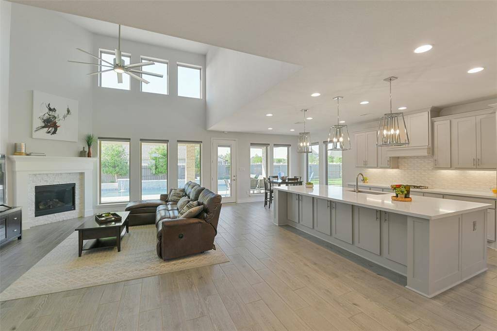 Enjoy entertaining or just relaxing in this amazing family room, kitchen, dining area, with 2 story ceilings in the living room, corner fireplace, ceramic wood-look tile throughout, huge kitchen, ample natural light, and views of the beautiful pool and backyard.
