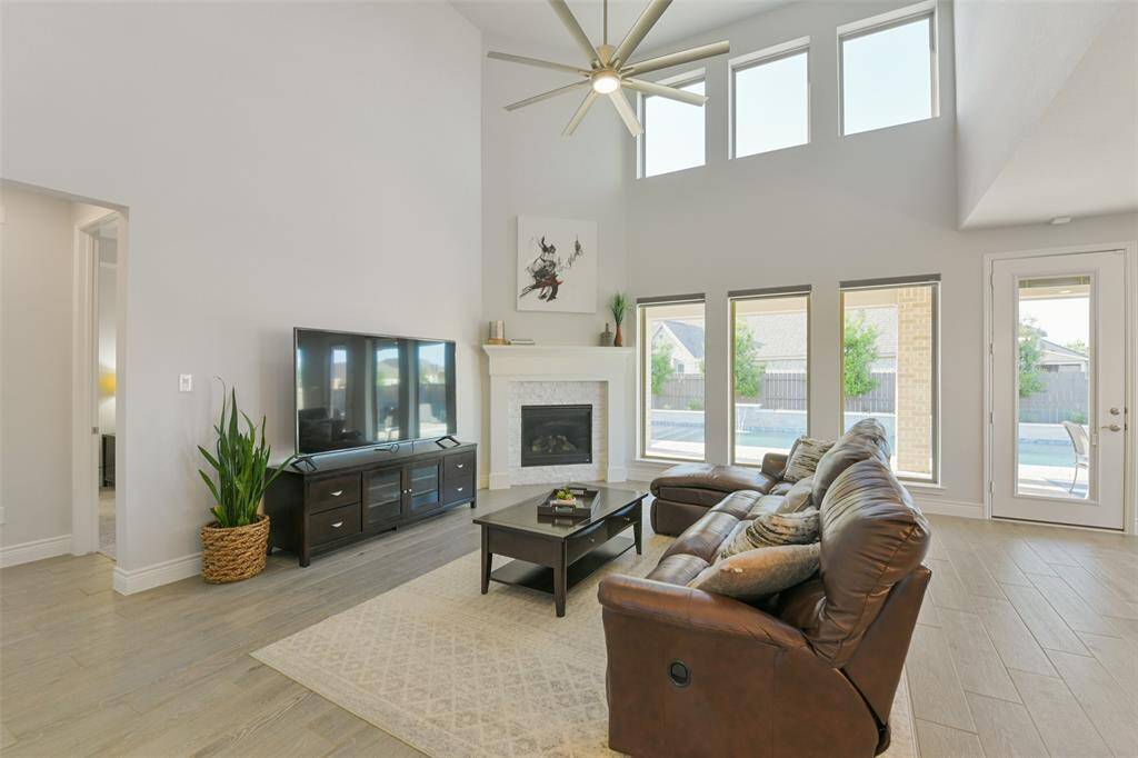 Family room has 2 story ceiling, corner fireplace, upgraded ceiling fan, and wall of windows with remote shades, plus an amazing view of the pool!