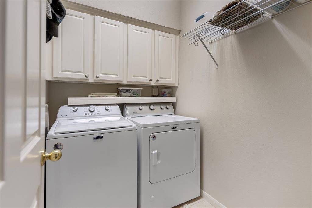 Laundry room with upper storage cabinets and hanging space.