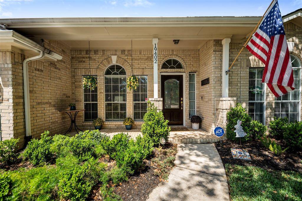 Inviting front porch framed by lush landscaping.