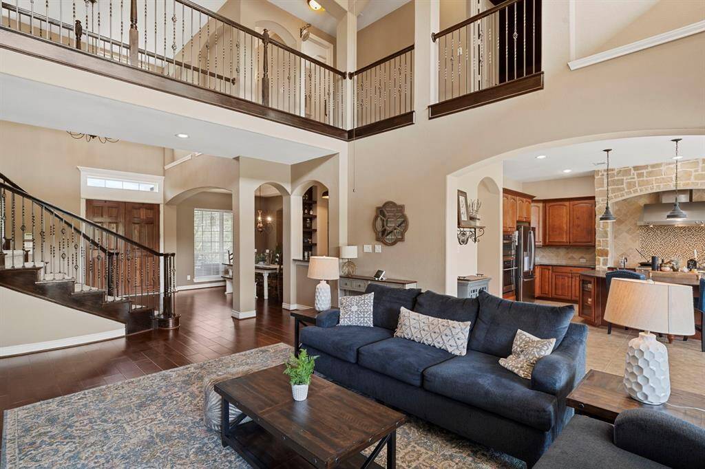 Spacious two-story living room with soaring ceilings, open sightlines, and seamless flow into the kitchen and foyer—perfect for both everyday living and entertaining.