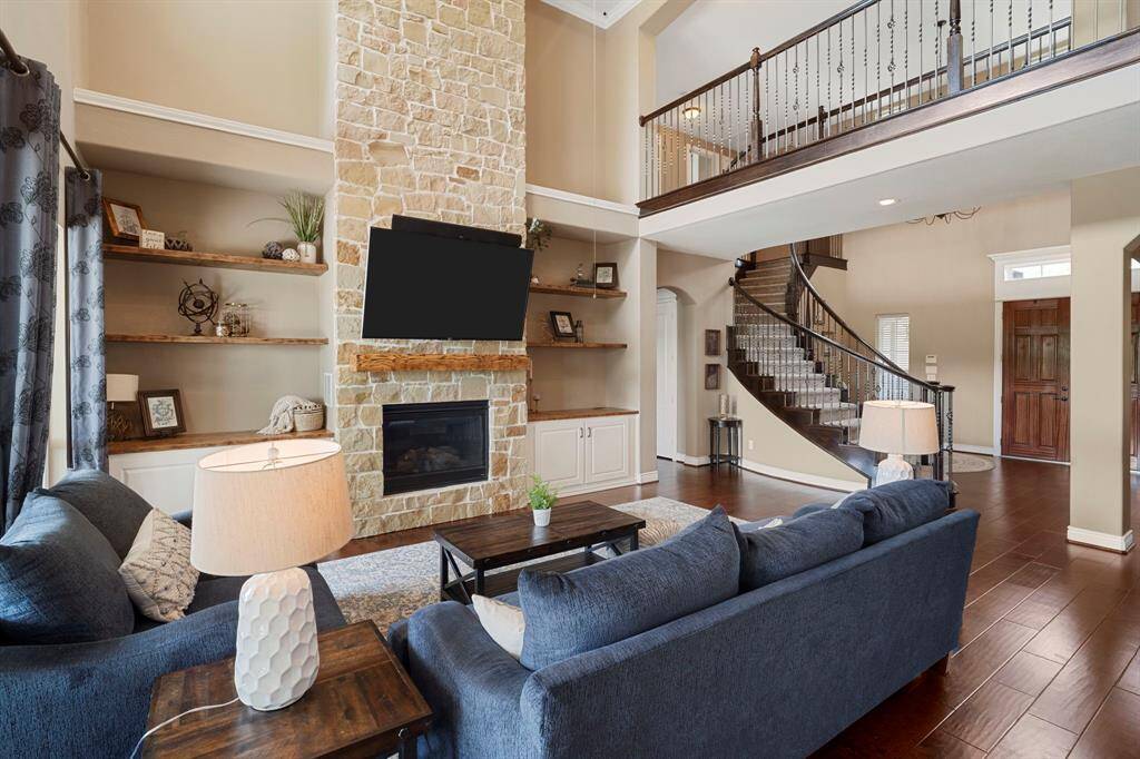 Cozy up in the inviting living area featuring a stunning floor-to-ceiling stone fireplace, built-in shelving, and abundant natural light.