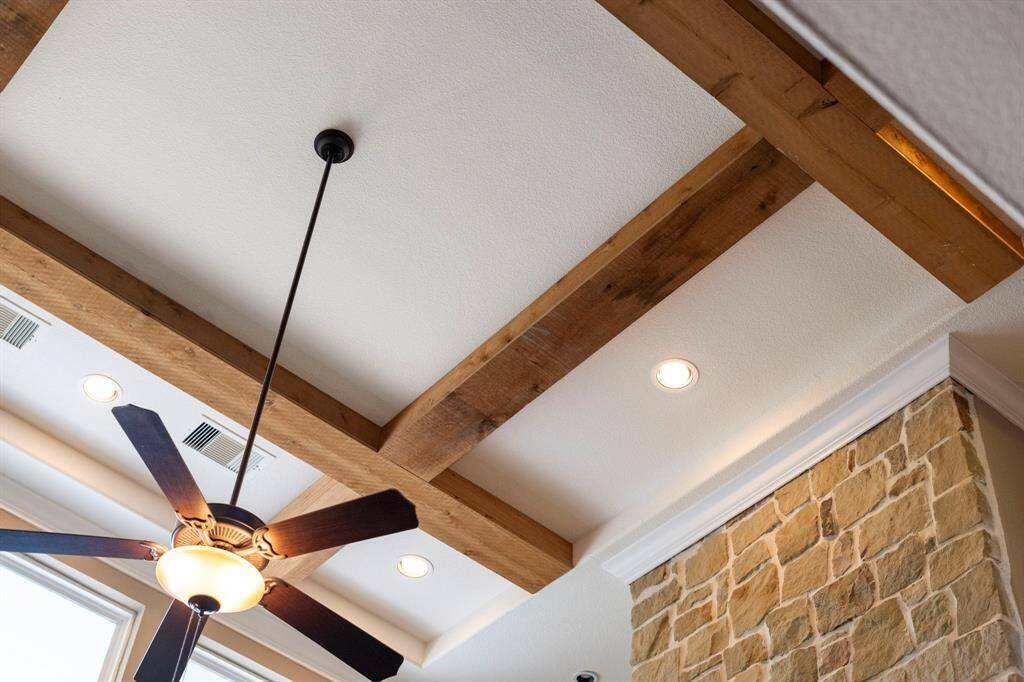 Eye-catching exposed wood beams and recessed lighting add warmth and architectural charm to the living space's vaulted ceiling.