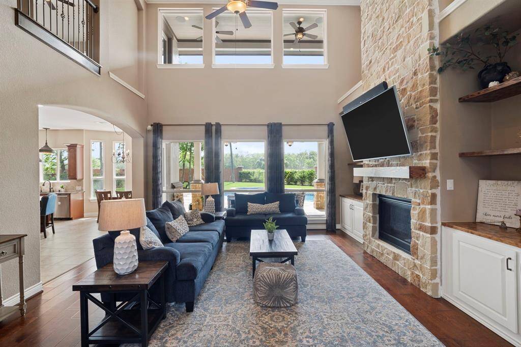 Soaring ceilings and expansive windows flood this living room with natural light, offering a seamless view of the backyard oasis and covered patio.
