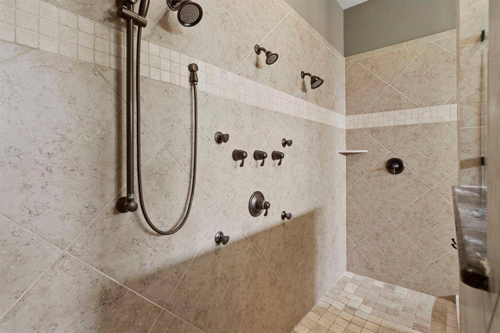 Indulge in a spa-like experience with this oversized walk-in shower featuring multiple body sprays, dual shower heads, and elegant tile work.