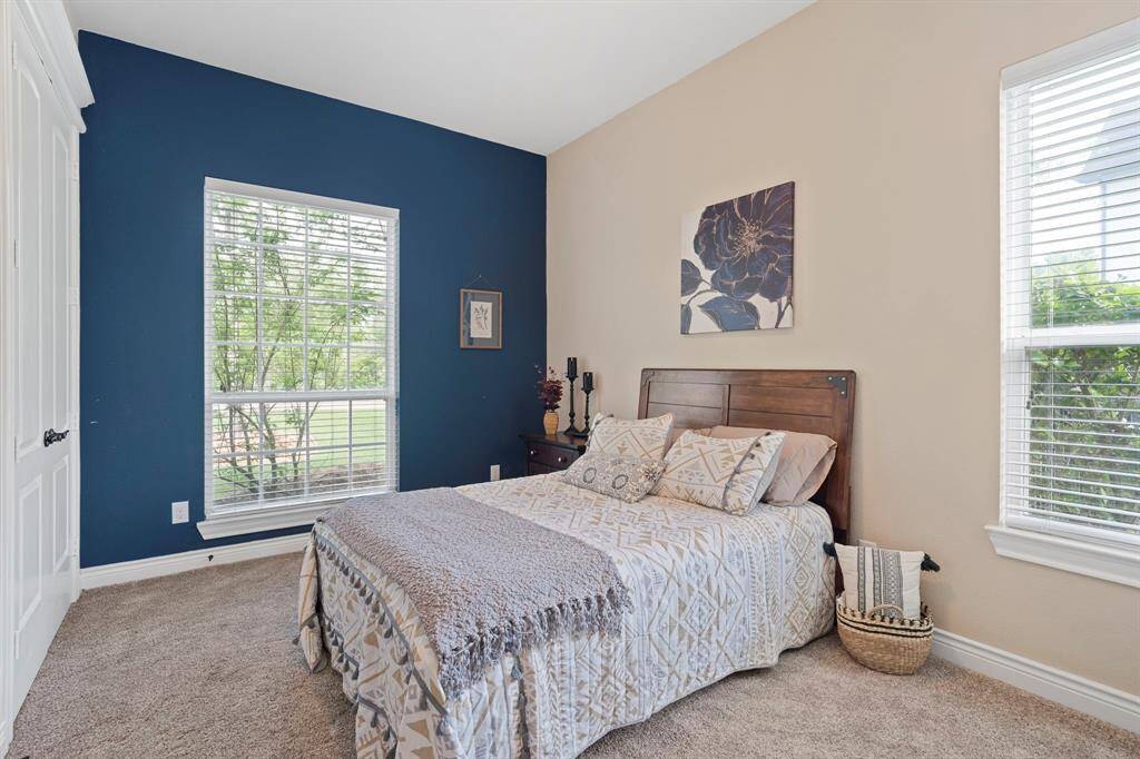 Charming guest bedroom with soft natural light, a bold accent wall, and peaceful views.