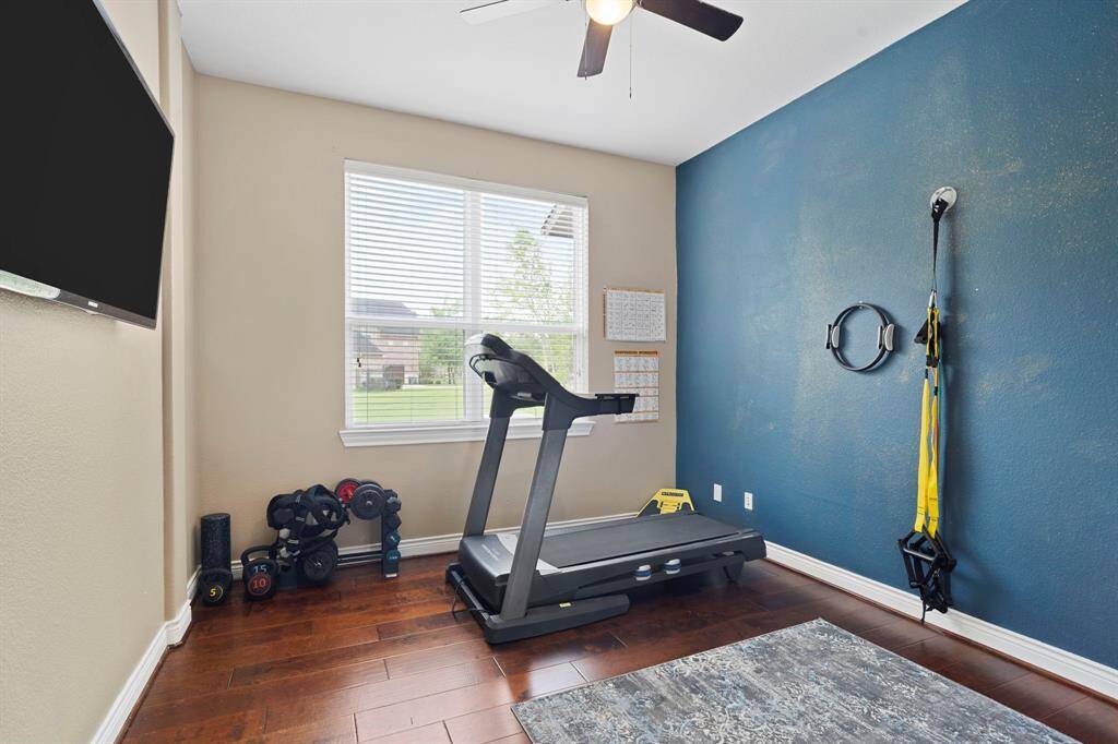 Fitness room, bedroom or flex space with hardwood floors and wall-mounted TV for at-home workouts or a personalized retreat.