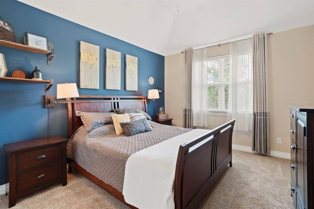 Inviting guest bedroom with high ceilings, soft carpet, and a bold navy accent wall for a modern, cozy touch.