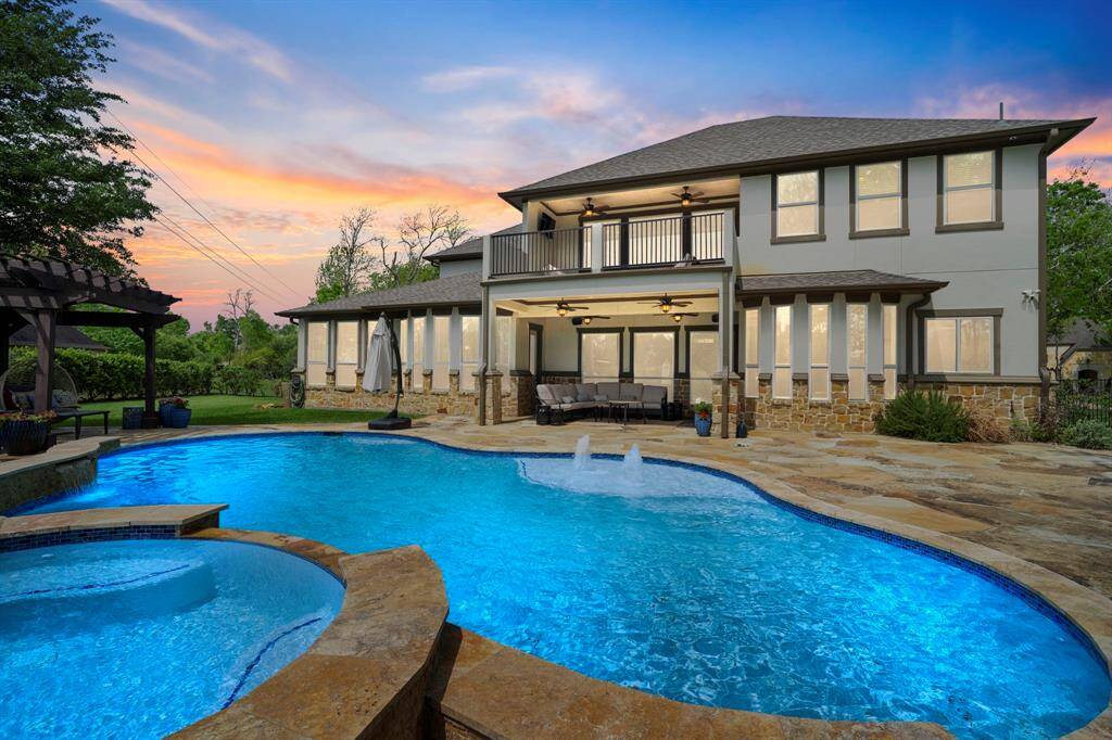 Resort-style backyard oasis featuring a sparkling pool, spa, and covered patio.