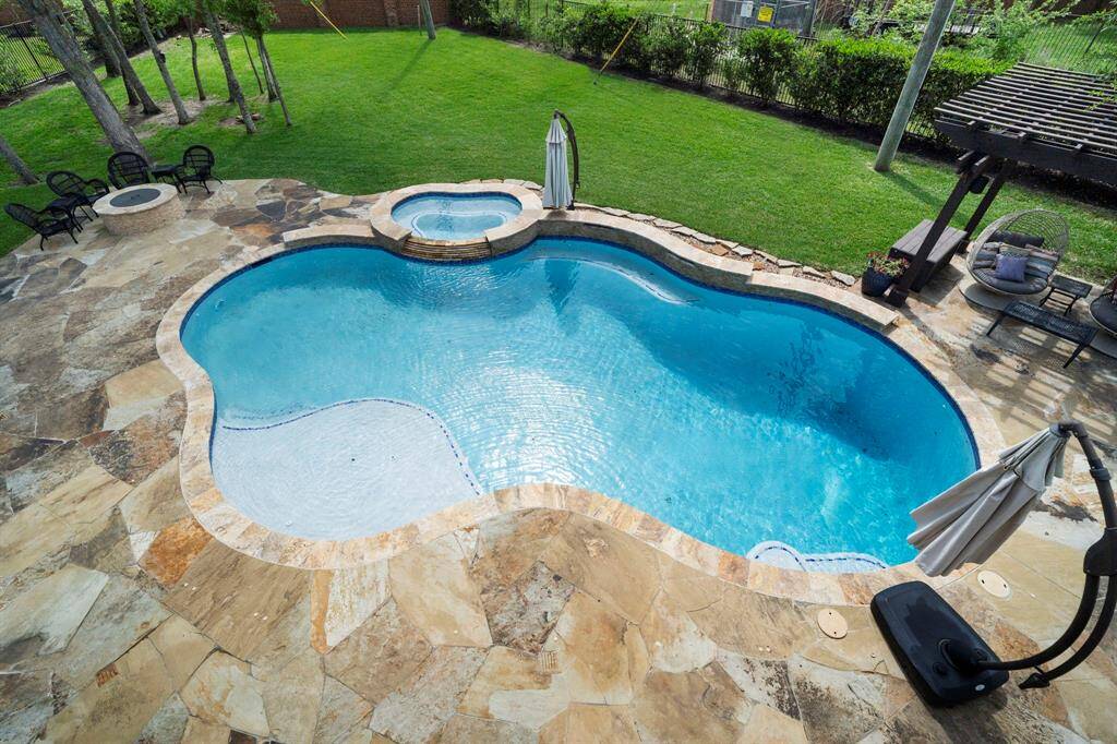 Enjoy a bird’s-eye view of the expansive backyard complete with a custom pool, spa, pergola, and lush lawn.