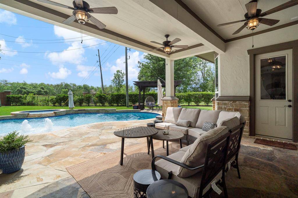 Relax in shaded comfort with a front-row view of the sparkling pool and lush backyard from the beautifully appointed covered patio.