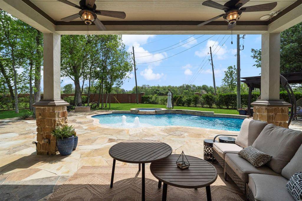 This inviting outdoor space offers seamless views of the pool, fire pit, and greenery bringing indoor comfort outside.