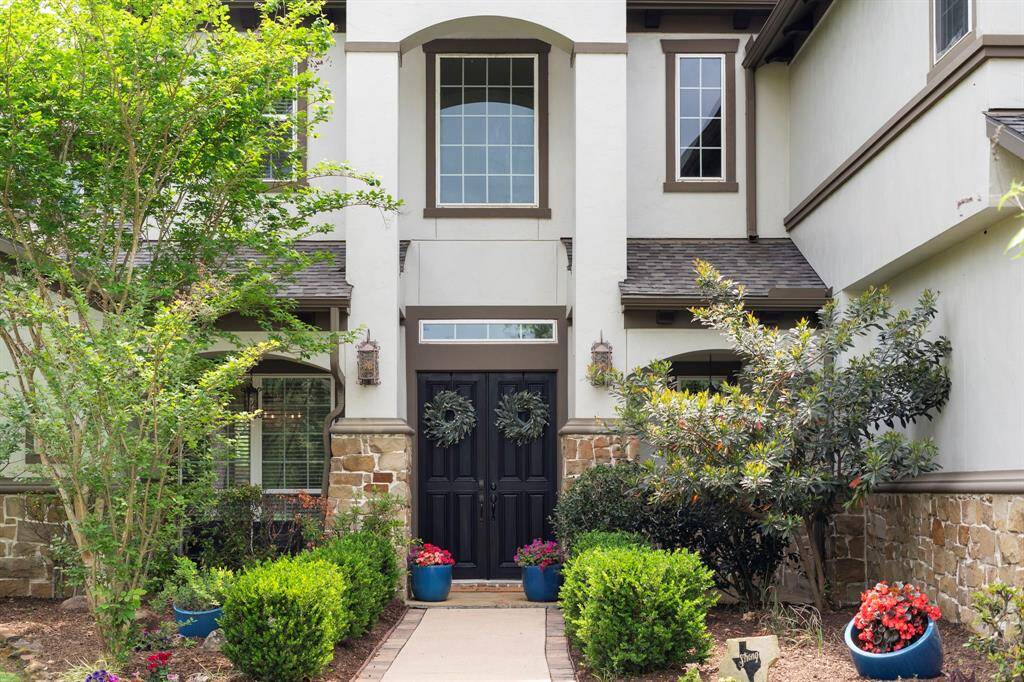 Charming curb appeal welcomes you home with lush landscaping, a stately stone-accented façade, and elegant double doors—setting the tone for luxury living inside and out.