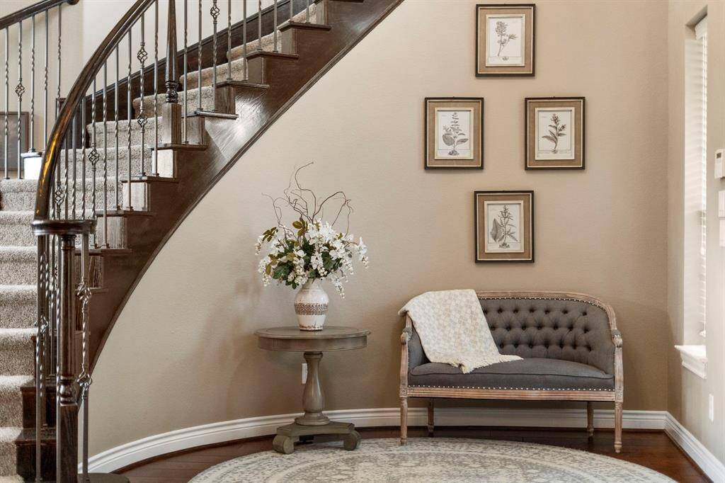 This elegant foyer nook beneath the curved staircase offers a warm, welcoming touch—perfect for quiet moments or stylish first impressions.